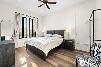 a white bedroom with a bed and a ceiling fan at The Artifact Hotel in San Diego