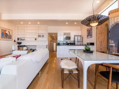 a living room with a white couch and a kitchen at La Jolla Condo Oceanview, Zen and Coastal Charm in San Diego