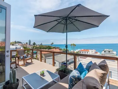 a patio with a couch and an umbrella at La Jolla Condo Oceanview, Zen and Coastal Charm in San Diego