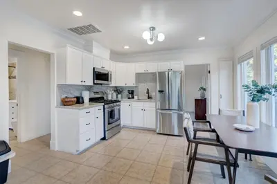 a kitchen with white cabinets and a table with chairs at Historic Barrio Logan Bungalow in San Diego