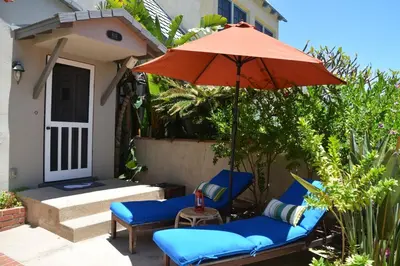a patio with two chairs and an umbrella at Charming Cottage with Parking, Bikes, Walk to Sand in San Diego