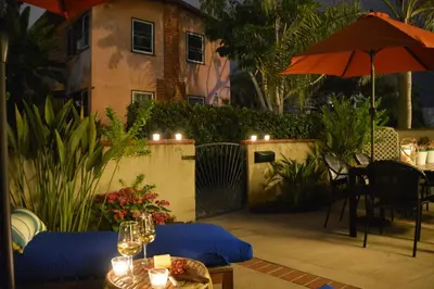 a patio with an umbrella and a table with wine glasses at Charming Cottage with Parking, Bikes, Walk to Sand in San Diego