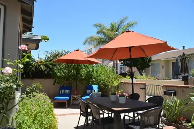 a table and chairs with umbrellas on a patio at Charming Cottage with Parking, Bikes, Walk to Sand in San Diego