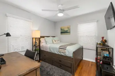 a bedroom with a bed and a desk and windows at Charming Cottage with Parking, Bikes, Walk to Sand in San Diego