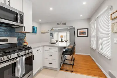 a kitchen with white cabinets and a stove at Charming Cottage with Parking, Bikes, Walk to Sand in San Diego