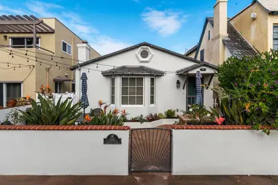a white house with a white fence and plants at Charming Cottage with Parking, Bikes, Walk to Sand in San Diego