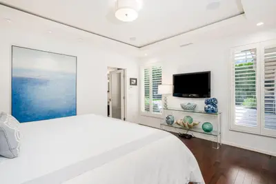 a white bedroom with a bed and a flat screen tv at La Jolla 3BR Oceanview Deck in San Diego