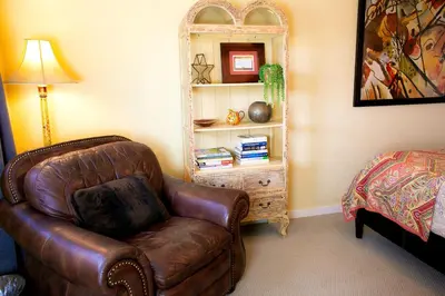a living room with a leather chair and a book shelf at Pet Friendly Fantastic Cottage with Hot-tub in Rainbow, California in Fallbrook