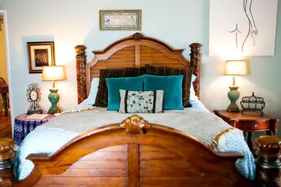 a bedroom with a large wooden bed with blue pillows at Pet Friendly Breathtaking Cottage with Hot-tub in Rainbow, California in Fallbrook