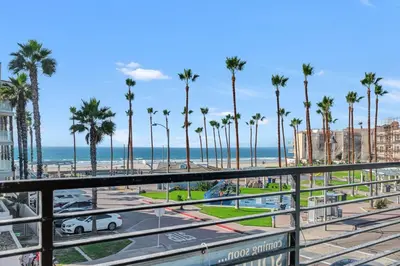a view of the beach from a balcony with palm trees at Steps to the Beach in Imperial Beach