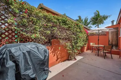 an outdoor patio with a table and an ivy covered wall at 1BD Heart of PB Pet Friendly Private Sanctuary in San Diego