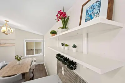 a kitchen with white walls and white shelves and a table at 15 Min to Beach and Zoo - Hot Tub - Cozy Fire Villa Pit in San Diego