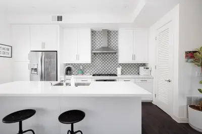 a white kitchen with white cabinets and black stools at Walk to Balboa Park and Little Italy LUX Townhome in San Diego