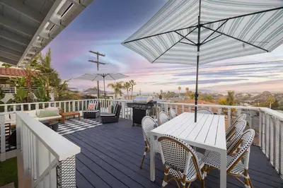 a deck with a table and chairs and an umbrella at Sunset Balcony Views 1 Mile to Beach 7 Beds in San Diego