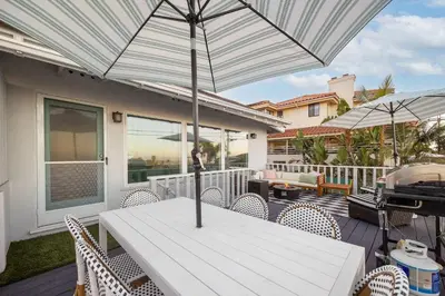 a white table and chairs with an umbrella on a deck at Sunset Balcony Views 1 Mile to Beach 7 Beds in San Diego