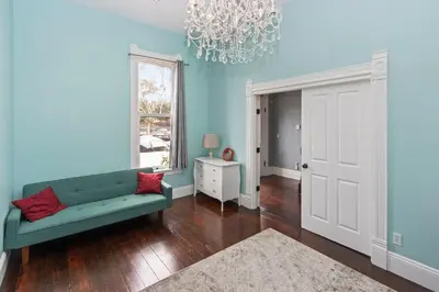 a living room with a green couch and a chandelier at 1900's Victorian Home Sleeps 22 8BDRM 3Bath in San Diego