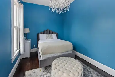 a blue bedroom with a bed and a chandelier at 1900's Victorian Home Sleeps 22 8BDRM 3Bath in San Diego