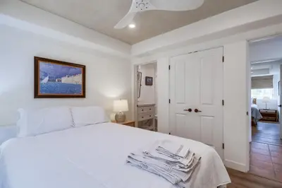 a white bedroom with a white bed and a door at Casa Hermosa in San Diego