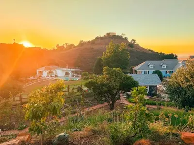 a house on a hill with the sunset in the background at Enchanted Estate With Animals Lightscapes and Whimsy in Bonsall