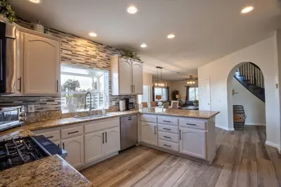 a large kitchen with white cabinets and wooden floors at Casa da Saudade in Temecula