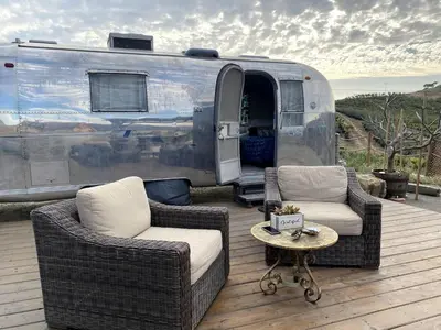 a patio with two chairs and a table in front of a trailer at Artsy Airstream for a California Glamping Weekend near San Diego in San Marcos