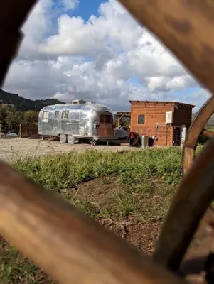 a silver trailer parked in a field with a building at Artsy Airstream for a California Glamping Weekend near San Diego in San Marcos
