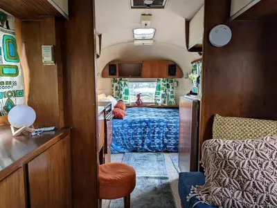 a room with a bed and a kitchen in a train at Artsy Airstream for a California Glamping Weekend near San Diego in San Marcos
