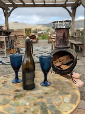 a bottle of wine and two blue glasses on a table at Artsy Airstream for a California Glamping Weekend near San Diego in San Marcos