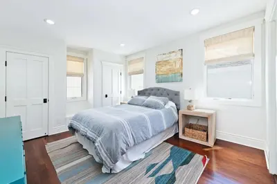 a white bedroom with a bed and two windows at Oceanfront Escape with Breathtaking Views in Newport Beach