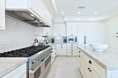 a white kitchen with a stove and a sink at Oceanfront Escape with Breathtaking Views in Newport Beach