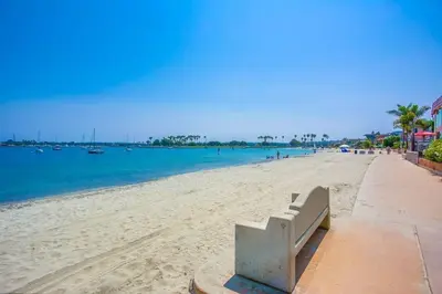 a bench sitting on a beach next to the water at Bali Beach in San Diego