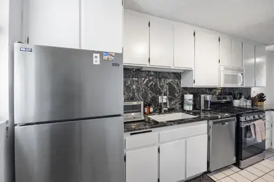 a kitchen with white cabinets and a stainless steel refrigerator at Shoreline Hideaway in San Diego