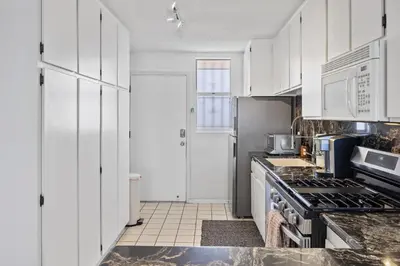 a kitchen with white cabinets and a stove top oven at Shoreline Hideaway in San Diego