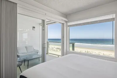 a bedroom with a bed and a view of the beach at Shoreline Hideaway in San Diego