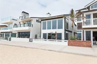 a building with a palm tree in front of it at Spacious Oceanfront Home Near Newport Pier in Newport Beach