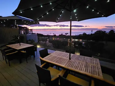 a patio with two tables and chairs and an umbrella at La Jolla Gem with Ocean View - 11 Beds, Hot Tub, Karaoke & Game Den in San Diego