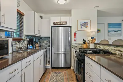 a kitchen with white cabinets and a stainless steel refrigerator at Dream 2 Story Home! Steps to the Ocean, Private Patio, AC, Hot Tub & BBQ in San Diego