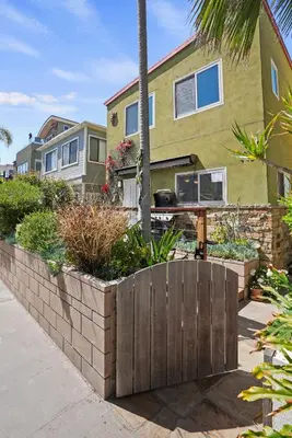 a house with a retaining wall and a palm tree at Dream 2 Story Home! Steps to the Ocean, Private Patio, AC, Hot Tub & BBQ in San Diego
