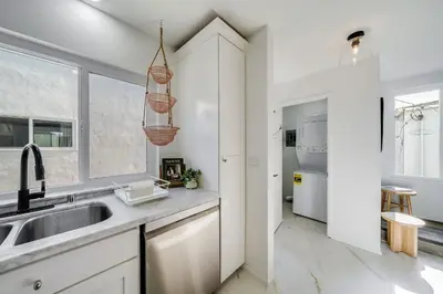 a kitchen with white cabinets and a sink at Boho Beach Bungalow Walk to the Beach in San Diego