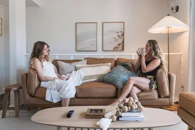 two women sitting on a couch in a living room at Boho Beach Bungalow Walk to the Beach in San Diego