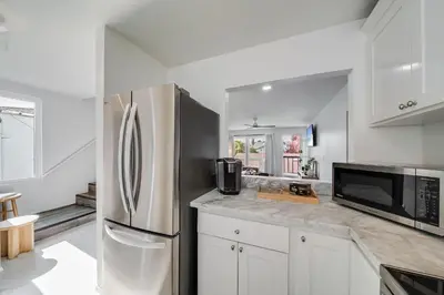 a kitchen with white cabinets and a stainless steel refrigerator at Boho Beach Bungalow Walk to the Beach in San Diego