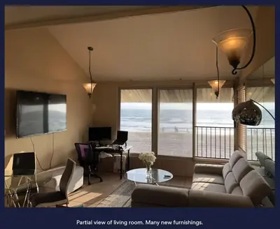 a living room with a couch and a table with a desk at Ocean Front Beauty right above Best Beach in Mission Beach, San Diego! in San Diego