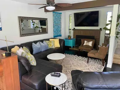 a living room with a leather couch and a fireplace at Tropical retreat for whole family Fresh eggs Made to Entertain in Carlsbad