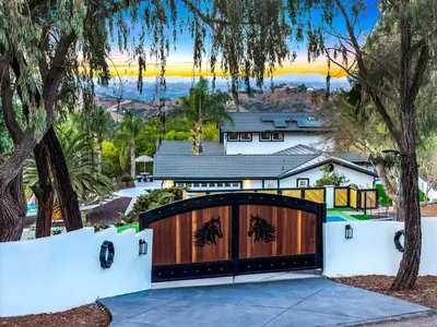 a house with a wooden garage door with trees at The Grand Vista Getaway in Vista