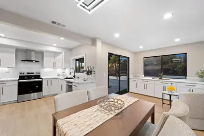 a kitchen with white cabinets and a table and chairs at The Grand Vista Getaway in Vista