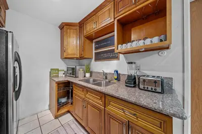 a kitchen with wooden cabinets and a sink and a refrigerator at Entire Private Home with 4 Bedrooms 2 Bathrooms, Garage & Gated Yard, Near San Diego Gaslamp, Beach, Available Now in National City