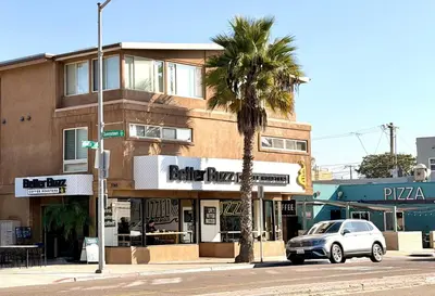 a car parked in front of a building with a palm tree at 2 Bdrm Condo + Parking in Heart of Mission Beach! in San Diego