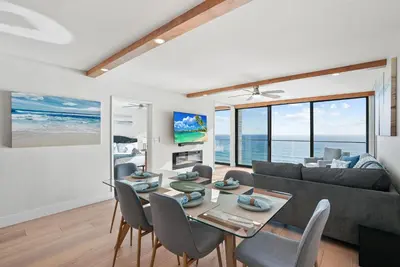 a living room with a table and a couch at Oceanfront Paradise with Sunset Balcony, Pool, Spa, Beach Access and Parking in San Diego