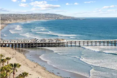 a beach with a pier and the ocean at Oceanfront Paradise with Sunset Balcony, Pool, Spa, Beach Access and Parking in San Diego