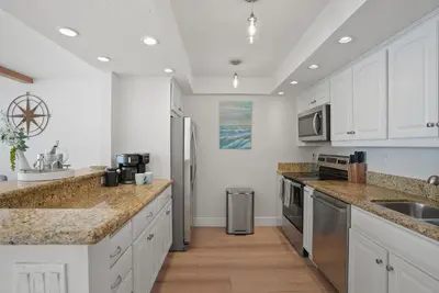 a kitchen with white cabinets and granite counter tops at Oceanfront Paradise with Sunset Balcony, Pool, Spa, Beach Access and Parking in San Diego